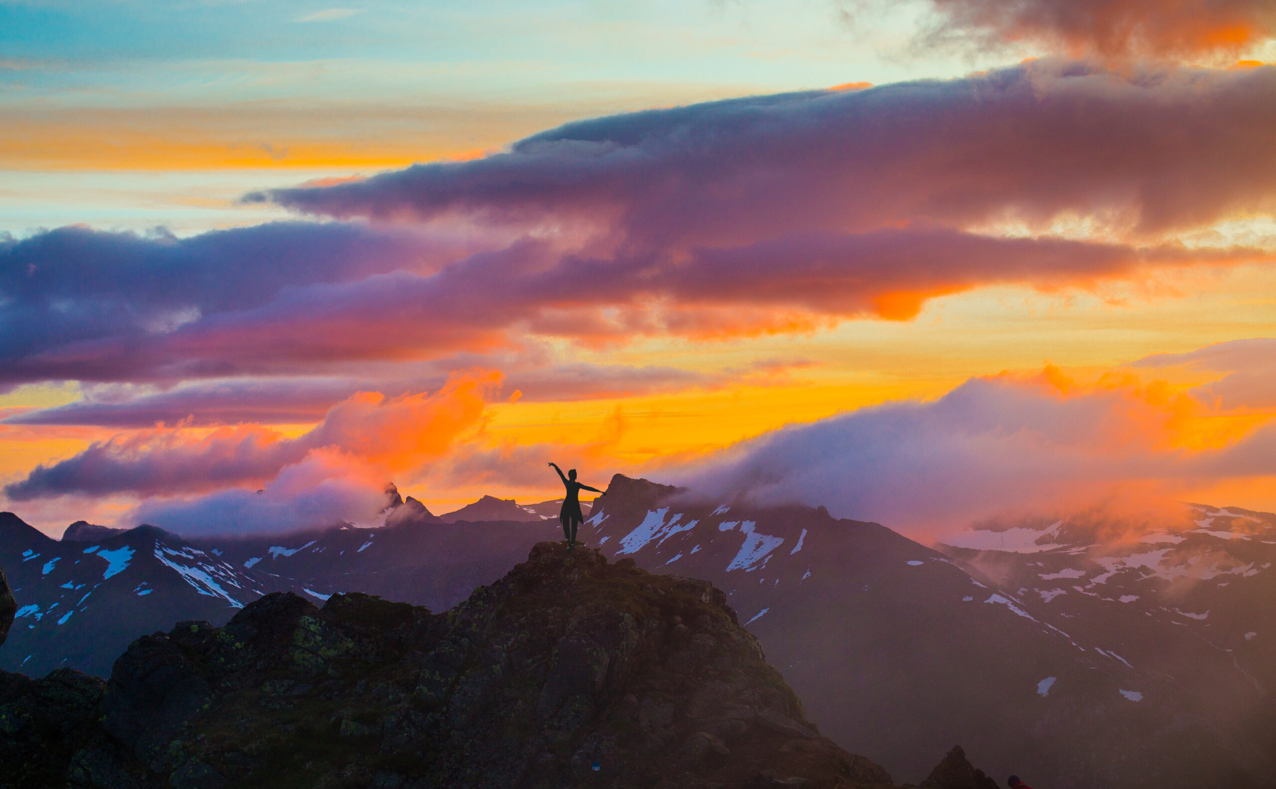 Woman dancing on the top of a mountain in Lofoten at sunset